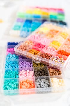Assorted clay bead boxes neatly arranged on a white table, awaiting a creative kids' craft project.