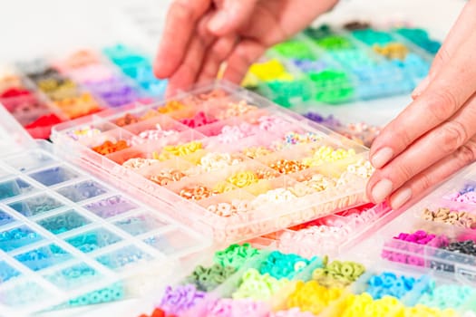 Assorted clay bead boxes neatly arranged on a white table, awaiting a creative kids' craft project.