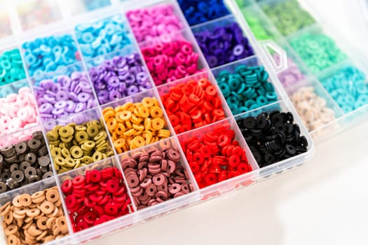 Assorted clay bead boxes neatly arranged on a white table, awaiting a creative kids' craft project.