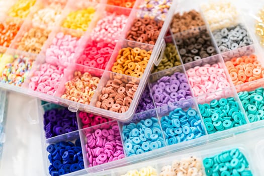 Assorted clay bead boxes neatly arranged on a white table, awaiting a creative kids' craft project.