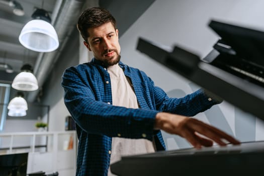 A focused musician plays a keyboard in a contemporary studio environment. Soft light filters through, while the artist deeply engages with the instrument, creating music.
