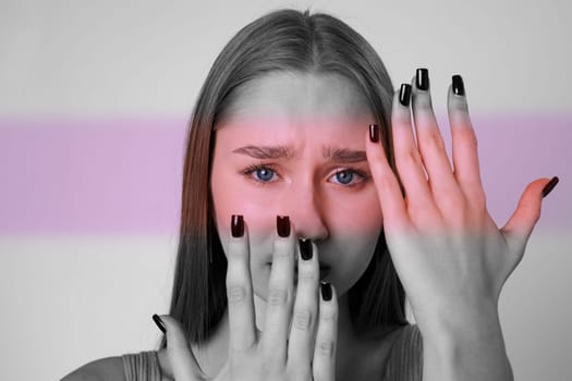 A young woman displays a range of emotions through her facial expression and hands. Her striking black nail polish contrasts with her soft features, capturing attention.