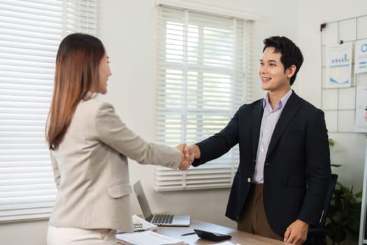 A professional handshake between two colleagues, symbolizing trust and partnership in a modern office environment.