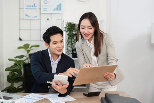 Two business professionals celebrate their success while discussing financial data, showcasing teamwork and motivation in a bright office.