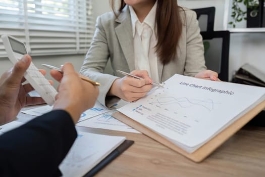 Business professionals analyze financial charts and documents during a consultation, utilizing a calculator for accurate assessments.