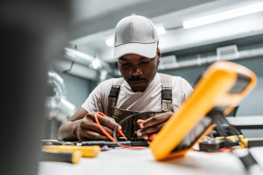 An electrician focused on troubleshooting a circuit board in a contemporary workshop. Various tools for electrical work are laid out, highlighting the hands-on nature of the task.