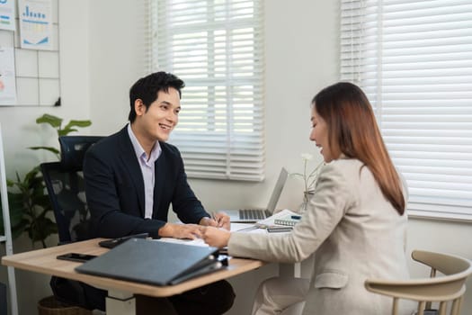 A businessman and businesswoman sharing insights and discussing financial strategies, fostering a positive work environment.