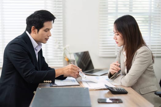 A client attentively reviews financial documents with an advisor, focusing on investment strategies in a professional environment.