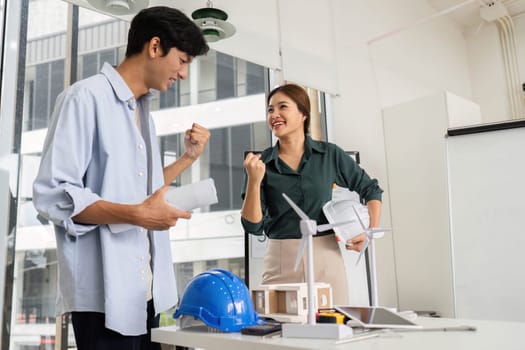 Two engineers express joy and excitement after a successful project discussion in a contemporary workspace.