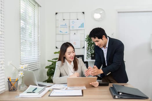 Two professionals collaborating on financial strategies, reviewing reports and charts at a contemporary office workspace.