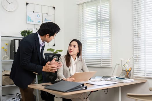 Two professionals discuss financial strategies and planning while reviewing documents in a modern workspace, showcasing teamwork and collaboration.