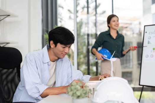 Two colleagues engage in a productive discussion about sustainable architecture, showcasing teamwork and innovation in a bright office environment.