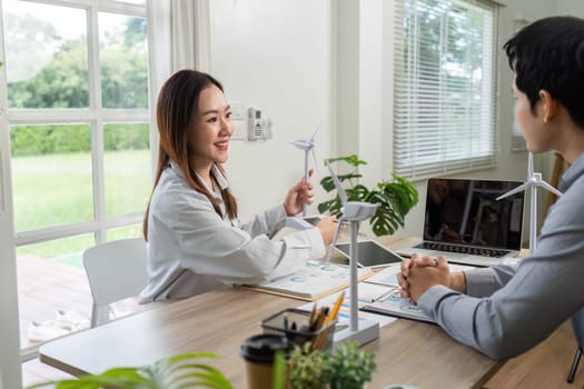 Two business professionals engage in a meeting focused on ESG initiatives, showcasing renewable energy models and data analysis.