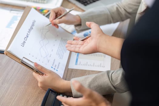Two colleagues analyze a line chart infographic, focusing on financial trends and insights during a meeting.