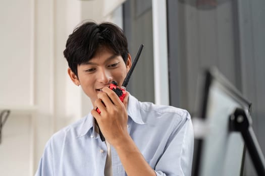 A young engineer communicates via walkie-talkie, ensuring smooth project coordination in a modern construction setting.