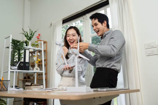 Two business professionals express joy and collaboration in a modern workspace, emphasizing ESG values and teamwork.