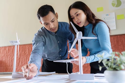A man and a woman work together on wind turbine models, focusing on innovative solutions for renewable energy.