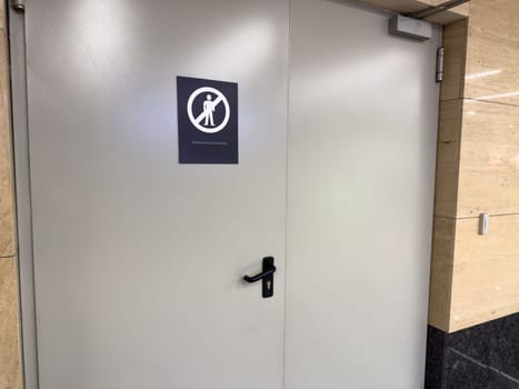 Closed metal door with a warning sign indicating Authorized personnel only in public building. Representing security measures, restricted access and staff only zones