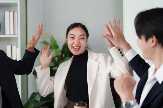 A vibrant office environment where colleagues celebrate a successful idea during a discussion. Their excitement reflects teamwork and innovation.