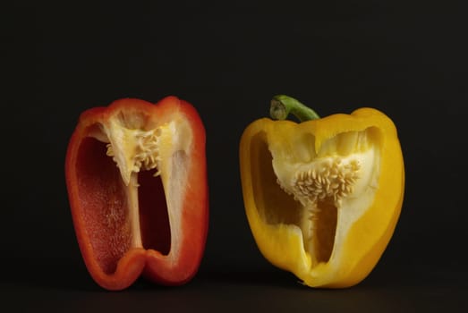 Pieces of yellow and red peppers on a black background in kitchen