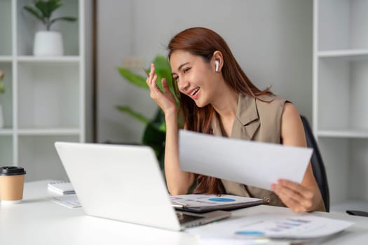 A young woman in a modern workspace smiles and reacts positively during a video meeting, showcasing the vibrant energy of remote work and collaboration.