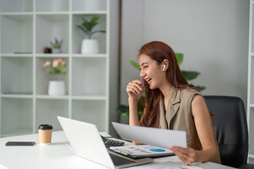 A young woman enjoys her work as she reacts joyfully to her screen, reflecting the positive aspects of teamwork in a digital environment.
