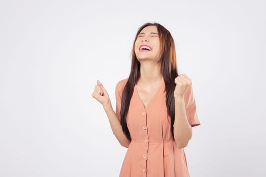 Excited businesswoman excited and overjoyed by success expresses victory with raised fists smiling brightly isolated studio white background symbolizing strength confidence and pride