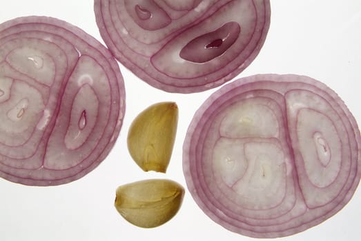 Cross section slice of red onion and garlic against light background on backligts