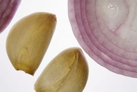 Cross section slice of red onion and garlic against light background on backligts