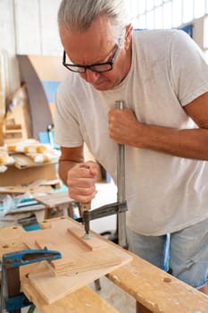 Senior carpenter working on wood craft at workspace producing wooden furniture. High quality photo