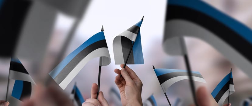 Estonia flags in their hands on a blurred urban background. The photo illustration was created without the use of artificial intelligence, only using Photoshop.