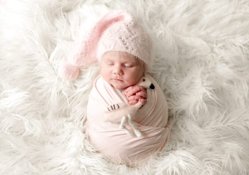 Newborn Baby Girl With Toy Sleeps At Studio Photoshoot