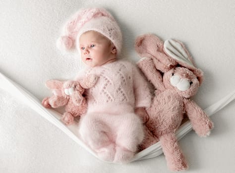 Studio Photoshoot Of A Newborn Baby Girl On A Swing With A Toy Bunny