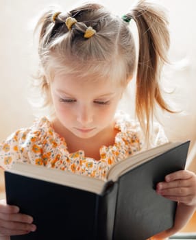 Close-Up Portrait Of A Sweet Girl Reading A Book