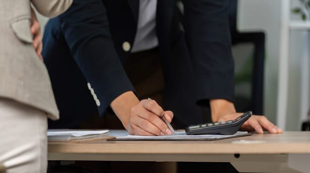 A businessman writing notes on financial documents during a discussion, emphasizing strategic financial planning.