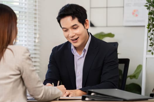 A businessman smiles while writing notes, engaging in a productive discussion about financial strategies.