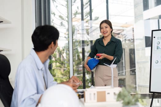A young woman presents ideas while a man takes notes, highlighting teamwork and innovation in sustainable design.