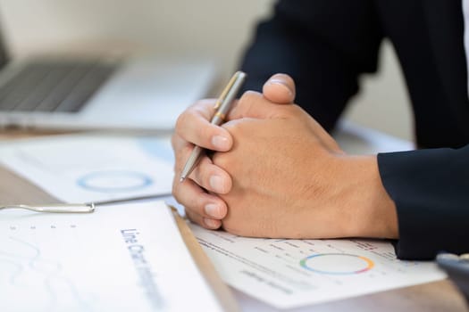 A businessman reflecting on financial reports and graphs, showcasing financial planning and analysis in a professional setting.