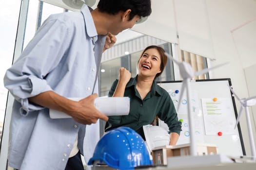 Engineers express excitement and joy while discussing their successful project in a modern office environment.