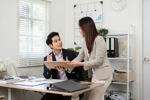 Two colleagues engage in a productive discussion about financial reports, showcasing teamwork and collaboration in a bright office environment.