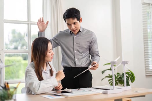 A man and woman engage in a lively discussion about ESG initiatives, emphasizing renewable energy solutions in a corporate setting.