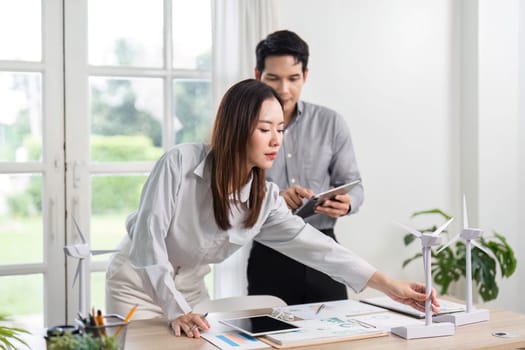 Business professionals actively engage in analyzing renewable energy concepts and ESG initiatives in a collaborative office environment.