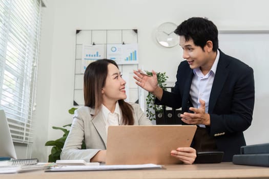 A male and female professional discussing financial data and strategies in a modern office environment, showcasing teamwork.