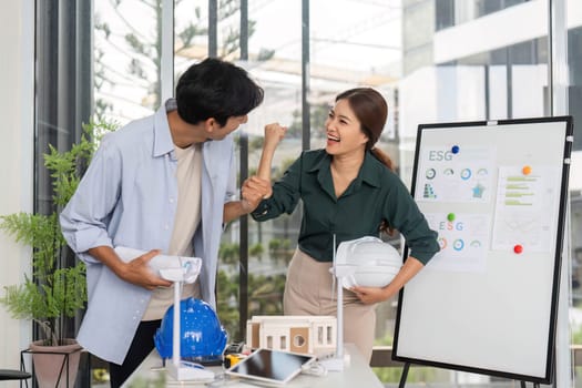 Two young engineers celebrate their project's success in a contemporary office, showcasing teamwork and enthusiasm for innovation.