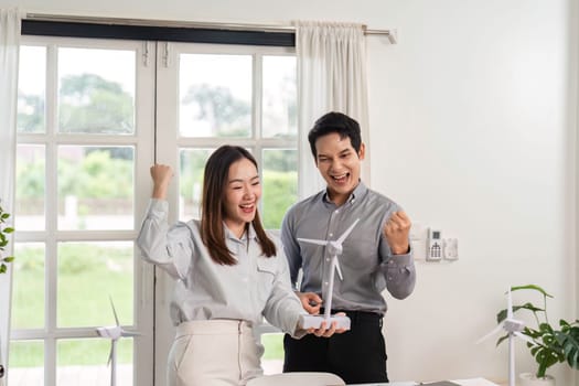 A man and woman enthusiastically discuss a wind turbine model, highlighting their commitment to ESG and innovative business practices.