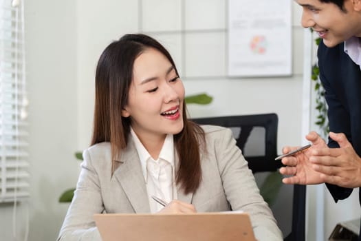 A businesswoman smiles while discussing financial strategies with her colleague, showcasing effective teamwork.