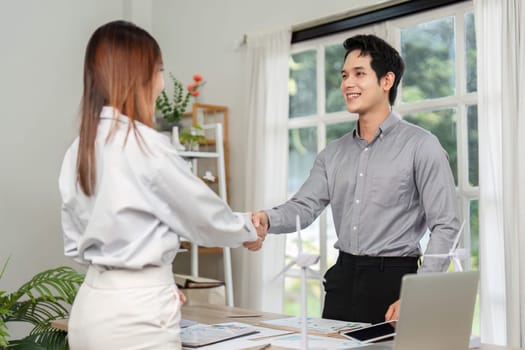 Two business professionals shake hands, finalizing an agreement on an ESG project focused on sustainability and innovation.