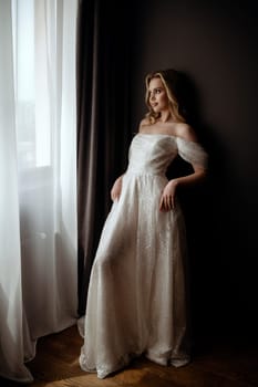 Elegant bridal gown showcased in a minimalist setting with a model in a chic pose during an indoor shoot. High quality photo