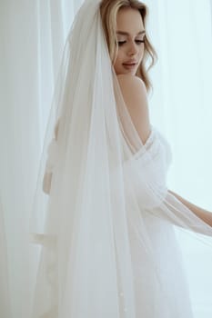 portrait of elegant blonde bride in white dress posing with veil close-up. Bride portrait, wedding makeup and hairstyle, fashionable bride. Beautiful bride in veil.