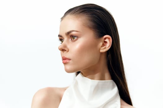 A portrait of a fashionable female model with long hair, exuding confidence and elegance in a sleek white attire, set against a minimalist white background.